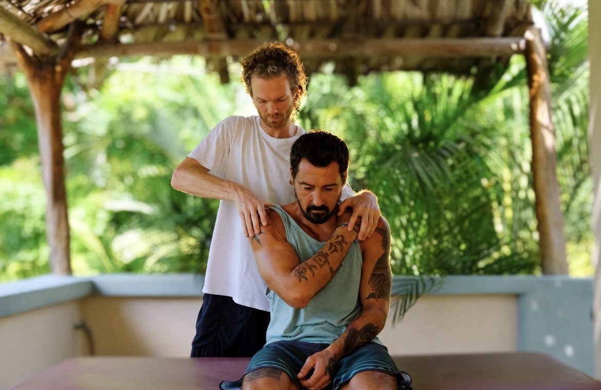 Jan releasing tension in a seated patient's shoulders